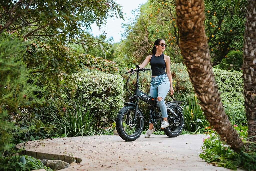 woman in black tank top with sunglasses riding on an electric bike